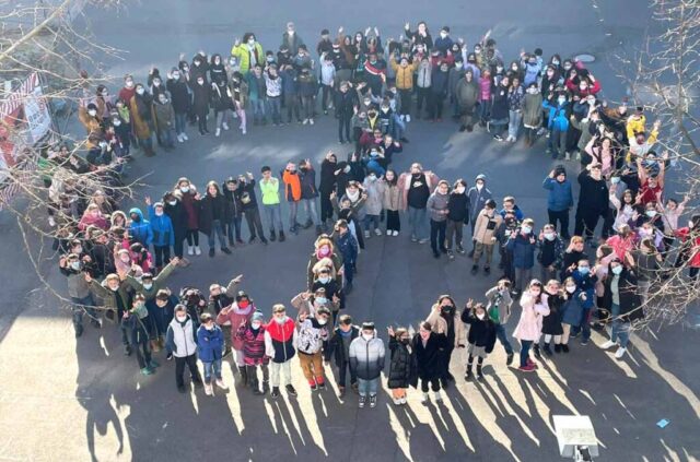 Schulhof mit Peace-Zeichen aus Kindern und Lehreren